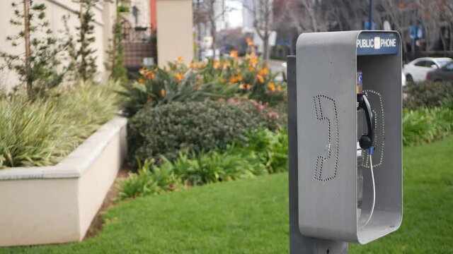 Retro coin-operated payphone station for emergency call on street, California USA. Public analog pay phone booth. Outdated technology for connection and telecommunication service. Cell handset on box.