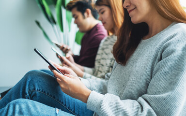 Group of young people using and looking at mobile phone while sitting together