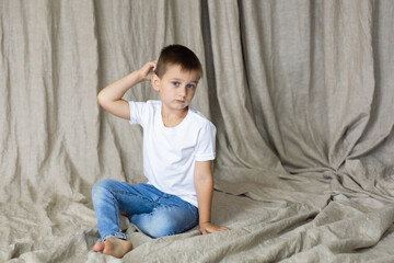 Cute little boy in white t-shirt posing. Portrait of a fashionable male child. Smiling boy posing. The concept of children's style and fashion.
