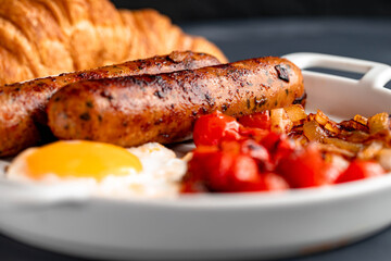 Delicious breakfast with sausage and fried egg combined with tasty caramelized onions and cherry tomatoes.