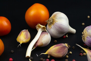 Ripe raw tomatoes, garlic on a black
