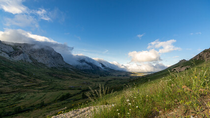 Panoramic photo in the valley of Arbas in Leon, Spain, with clouds passing over the peaks towards the valley