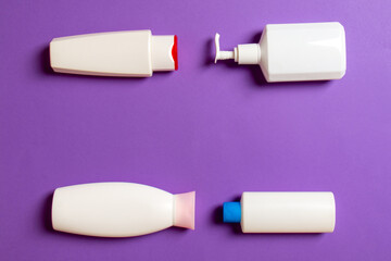 Set of White Cosmetic containers isolated on colored background, top view with copy space. Group of plastic bodycare bottle containers with empty space for you design