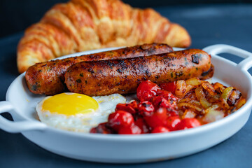 Delicious breakfast with sausage and fried egg combined with tasty caramelized onions and cherry tomatoes.
