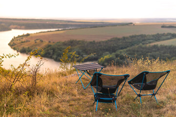 lightweight and compact equipment. Folding chairs and a table stand on the banks of the river. Tourism equipment in nature in a natural environment. Equipped holiday camp. no bodies