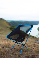 lightweight and compact equipment. Folding chair stand on top of the mountain. Tourism equipment in...