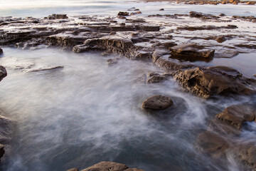 Fototapeta na wymiar Water around the rocky platform in the beach.
