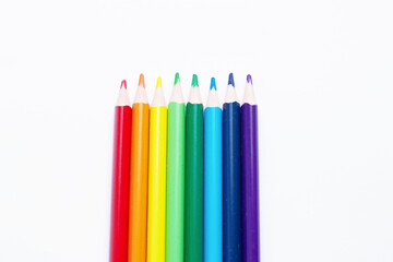 multicolored pencils, rainbow colors, lie vertically in the center, on a light, white background. Creative advertising of pencils for drawing. Subjects for creativity, art school,