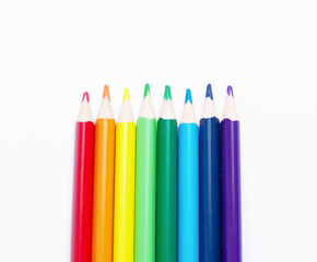 multicolored pencils, rainbow colors, lie vertically in the center, on a light, white background. Creative advertising of pencils for drawing. Subjects for creativity, art school,