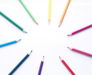 multicolored pencils, rainbow colors, chaotically laid out in the form of the sun, on a light, white background. Scattered multicolored pencils. Subjects for creativity, art school. Pencil sun