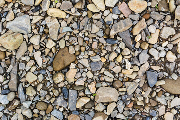 The texture of small river stones. Brown, yellow, blue and blue colors. Background with space for text. Camping. Bank of the river, sea, ocean.