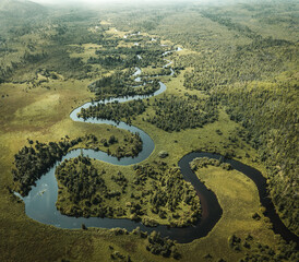 A winding river flows among forests and meadows. Drone shot