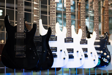 Fototapeta na wymiar Black and white electric guitars hanging in row in musical shop