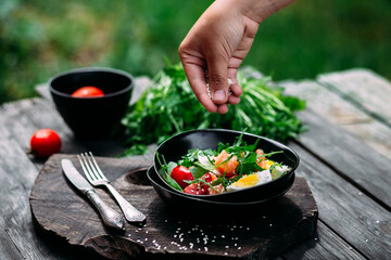 Salad with salmon, arugula and egg in a black plate 