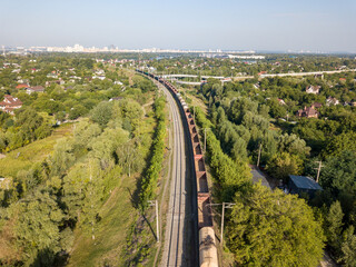 Aerial drone view. Freight train travels by rail in the city.