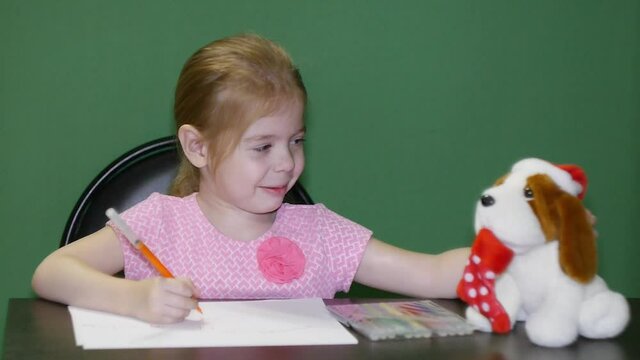 A girl with a toy dog composes a letter to Santa Claus chromakey to replace the background