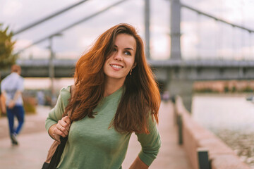 Fototapeta premium A young brunette woman with a backpack walks along the embankment in Moscow