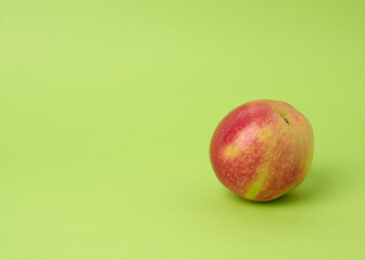 ripe red round apple on a green background, autumn harvest, close up