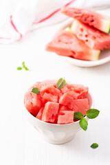 Juicy ripe sweet red watermelon slices with mint leaves in a bowl on a white background, delicious summer berries