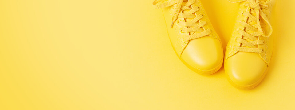 Banner with pair of yellow shoes on yellow background. Minimal styled, shot at angle.