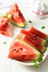 Juicy ripe sweet red watermelon slices with mint in a plate on a white background