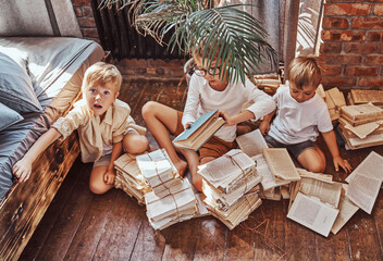 Children from one family learning and resting sitting on floor in kindergarten. Brothers having a good time together.