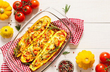 Stewed yellow zucchini with tomatoes and onions, cheese and herbs, carrots and spices, stuffed zucchini on a white wooden background