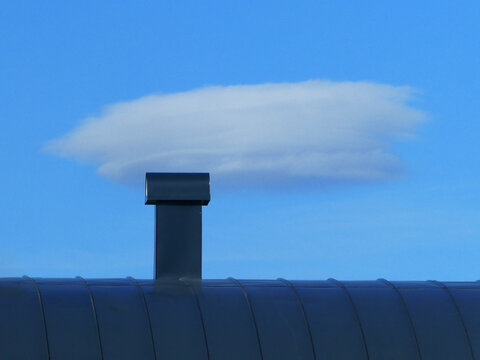 Clouds on the blue sky like a smoke from the chinmey on the roof