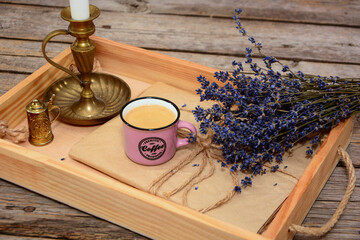 Composition of cup, mug of coffee with lavender and candlestick on wooden tray o9n wooden background. Vintage, retro card.  Coffee concept.  