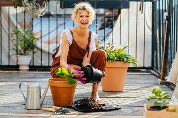 Beautiful amazing blond romantic woman among flowers at her balcony during planting.