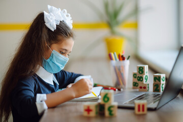 Online remote learning. School girl  in medical mask with computer having video conference chat with teacher and class group. Homeschooling during quarantine. Covid-2019.