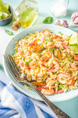 Orzo pasta with cream sauce and seafood. Homemade Orzo with various seafoods and shrimps, with lemon slices on light blue background copy space top vuew