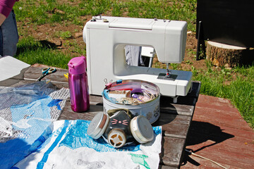 Homemade respirator, a box of sewing items, a sewing machine and plastic materials on the table