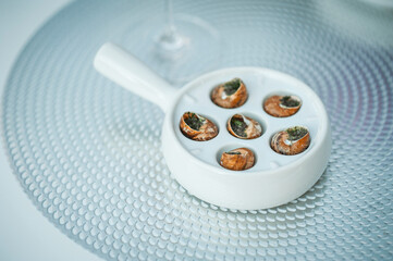 Delicious dish with stuffed snails under different sauces on white background. Dish of snails on a plate close up. Snails baked with butter and spices