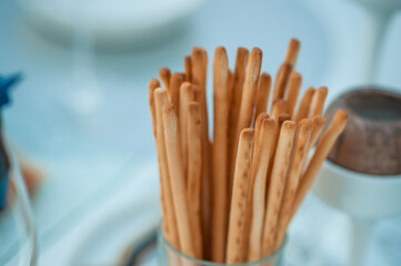Fresh homemade crispy bread sticks with sea salt on set white table with fresh herbs. selective focus. Italian cuisine, snack to wine