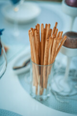 Fresh homemade crispy bread sticks with sea salt on set white table with fresh herbs. selective focus. Italian cuisine, snack to wine