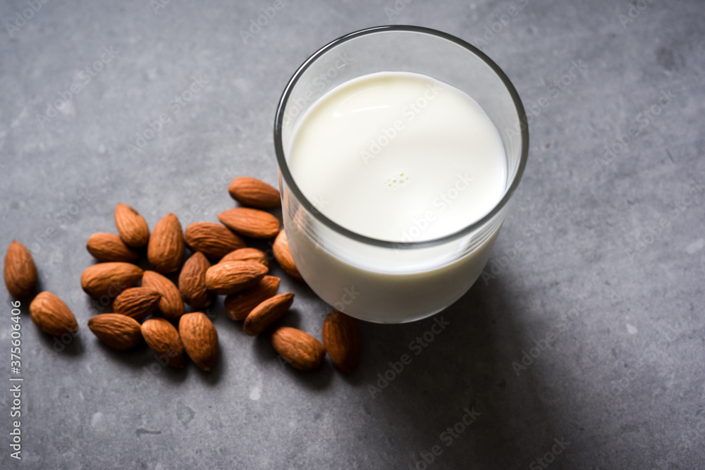 Wall mural Almond milk in a glass with almond ingredients on table