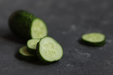 Fresh cucumber and slices close-up on a dark background.