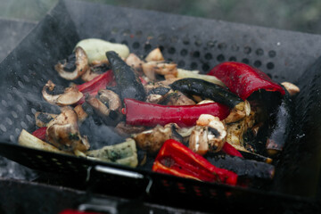 Eggplants, mushrooms, bell peppers in a grill pan on the grill. Grilled vegetables