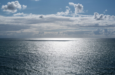 Blue calm ocean and sky with white clouds