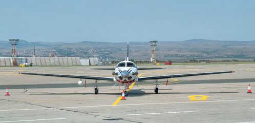 Front view of single engine piston turboprop powered light aircraft on the apron of airport. Modern...