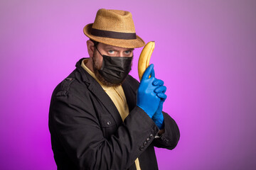 a man in a mask and a hat holds a banana in his hands like a gun