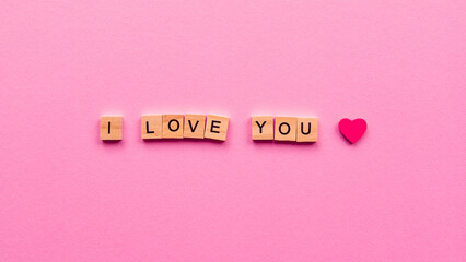 Words "I love you" on a pink paper background. Can be used as greeting card for wedding, anniversary, Women's Day or Valentine's Day.