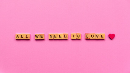 Words "All we need is love" on a pink paper background. Can be used as greeting card for wedding, anniversary, Women's Day or Valentine's Day.