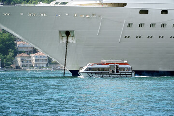  A small pleasure boat on the background of a large cruise liner.