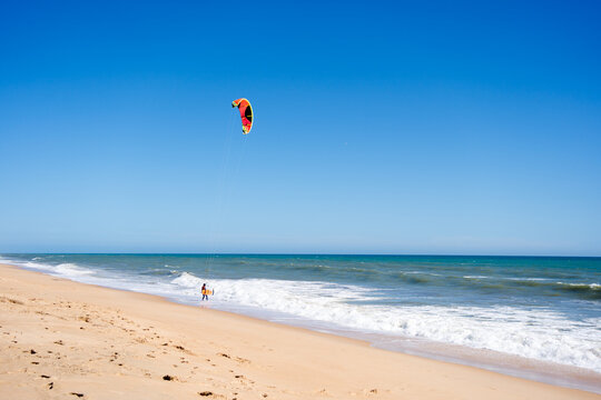 Beautiful kiteboarding surfing with golden sand sea water. Kite in the air on the beach, sunny outdoors background.