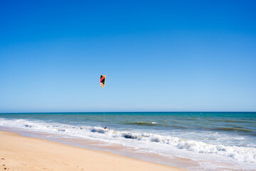 Beautiful kiteboarding surfing with golden sand sea water. Kite in the air on the beach, sunny outdoors background.