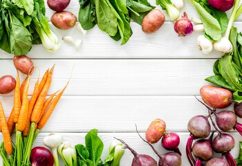 Flat lay of fresh vegetables and greenery on white table top-down copy space