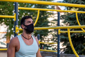Strong young latin man doing calisthenics with mask
