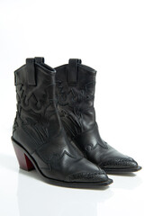 Fashionable female black leather cowboy boots isolated on a white background.